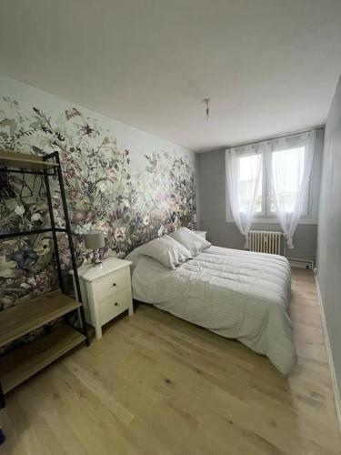 - une chambre avec un lit et un mur fleuri dans l'établissement Appartement urbain à deux pas de la plage, au Havre