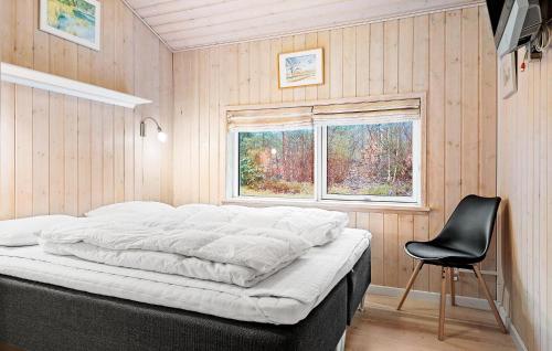 a bed in a room with a chair and a window at Awesome Home In Ebeltoft With Sauna in Ebeltoft