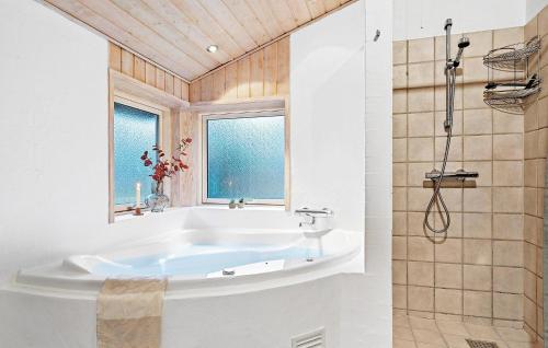 a white bathroom with a tub and a window at Awesome Home In Ebeltoft With Sauna in Ebeltoft