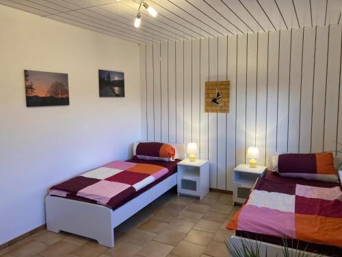 een slaapkamer met 2 bedden en 2 lampen erin bij Ferienwohnung Weinbachtal in Wallerfangen
