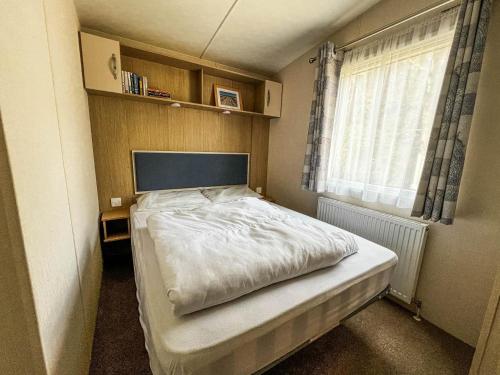 a small bedroom with a bed and a window at 6 Berth Luxury Caravan With Full Sea Views At Azure Seas In Suffolk Ref 32069az in Lowestoft