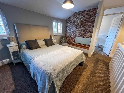 a bedroom with a bed and a brick wall at Beautiful 04 Berth Cottage With A Private Hot Tub In Norfolk Ref 99002hc in Pentney