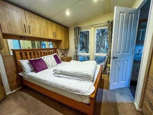 a bedroom with a bed with white sheets and purple pillows at Pet Friendly, Luxury Caravan For Hire In Suffolk By The Beach Ref 32203og in Lowestoft