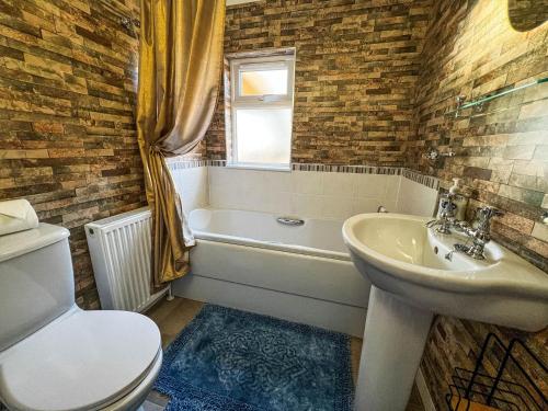 a bathroom with a sink and a tub and a toilet at Bespoke Holiday Home With Private Pool And Hot Tub, Sleeps 8 Ref 34073p in Kings Lynn