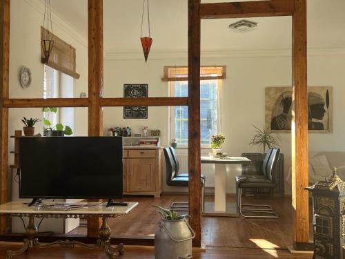 een woonkamer met een grote televisie en een tafel bij Sandys Cozy Stone Cottage in Maulbronn