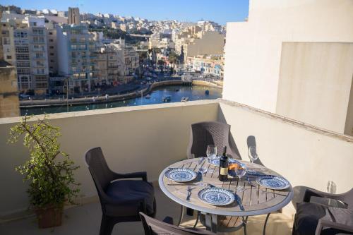 a table on a balcony with a view of a city at Stylish Saint Julians 1 bedroom Penthouse with Terrace in the city centre with Seaview in St. Julianʼs