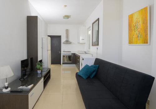 a living room with a black couch and a kitchen at Stylish Saint Julians 1 bedroom Penthouse with Terrace in the city centre with Seaview in St. Julianʼs