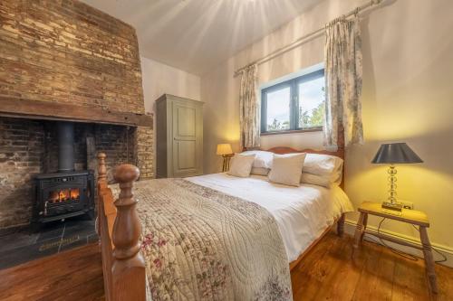 a bedroom with a bed and a fireplace at Pettingalls Farm Cottage in Great Ellingham