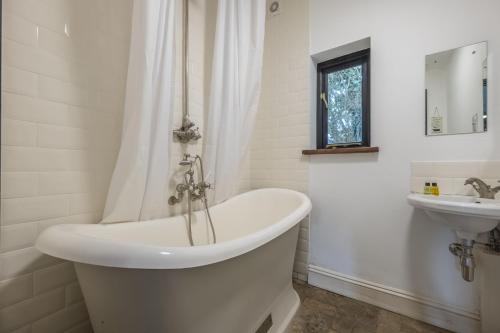 a white bathroom with a tub and a sink at Pettingalls Farm Cottage in Great Ellingham