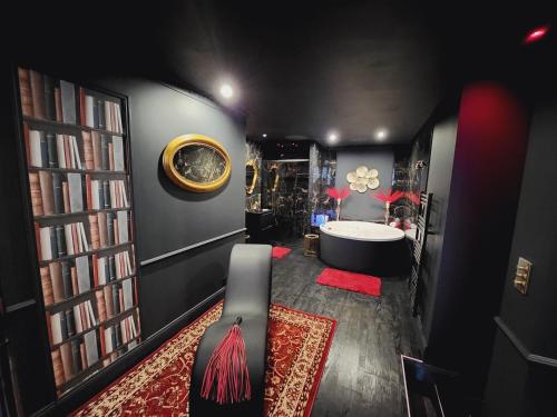 een zwarte kamer met een bad en een bibliotheek bij O' Plaisirs Interdits - Loveroom in Caen