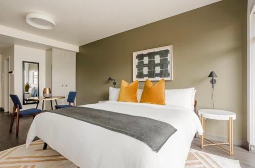 1 dormitorio con 1 cama blanca grande con almohadas de color naranja en Resort Inn Centrum en Szczecin
