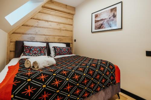 a bedroom with a bed with a wooden wall at VisitZakopane - Premium Best View&Spa Apartment in Zakopane