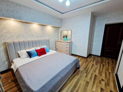 um quarto com uma cama grande com almofadas azuis e vermelhas em Просторная 3 комнатная квартира em Taraz