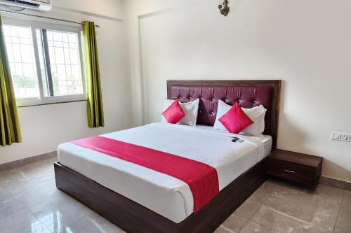 a bedroom with a large bed with pink pillows at FabHotel KSP Kings Inn in Bangalore