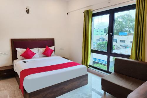 a bedroom with a bed with red pillows and a window at FabHotel KSP Kings Inn in Bangalore