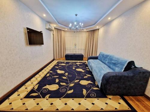 a living room with a blue couch and a rug at Просторная 3 комнатная квартира in Taraz