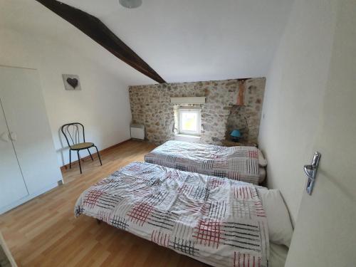 a bedroom with two beds and a chair in it at La Cour des Miracles in Vallon-Pont-dʼArc