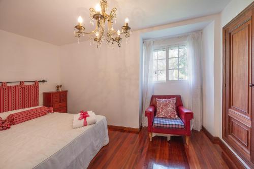 a bedroom with a bed and a chandelier and a chair at YourHouse A Casa Dos Cregos in Fonteita
