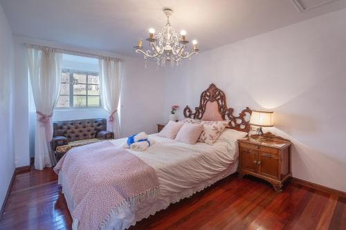 a bedroom with a large bed and a chandelier at YourHouse A Casa Dos Cregos in Fonteita