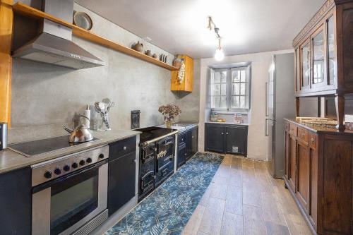 een keuken met zwarte apparatuur en een blauw tapijt op de vloer bij YourHouse A Casa Dos Cregos in Fonteita