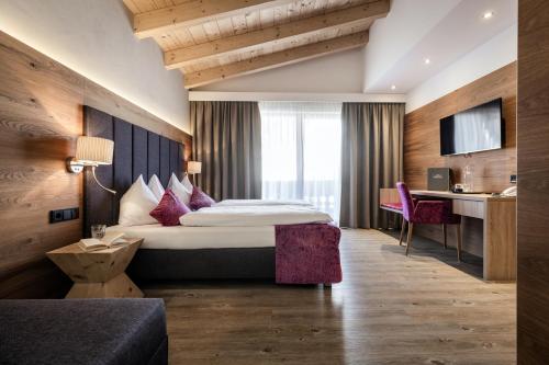 a hotel room with a bed and a desk at Hotel Sonnegg in Saalbach Hinterglemm