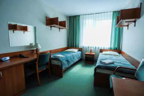 a hotel room with two beds and a desk at Hotel Krakowiak in Krakow
