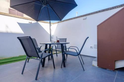 a table and chairs with an umbrella on a patio at Le dimore di Calù in San Donato di Lecce