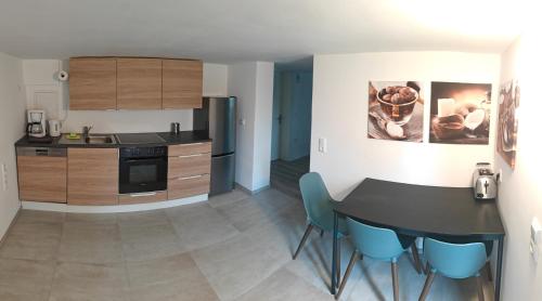 a kitchen with a black table and blue chairs at Goldbergsee-Apartment in Coburg