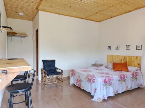 1 dormitorio con 1 cama, mesa y sillas en Pousada Rota da Serra, en Munhoz