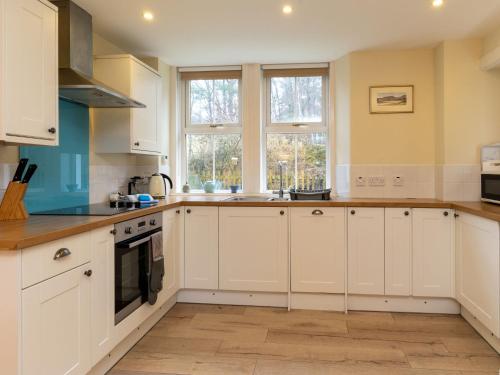 a white kitchen with white cabinets and windows at Holiday Home 1 Railway Cottage by Interhome in Aviemore