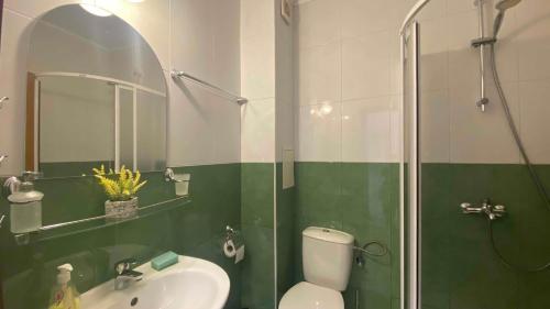 a green and white bathroom with a toilet and a shower at Bratanov Yassen Holiday Vilage in Sunny Beach