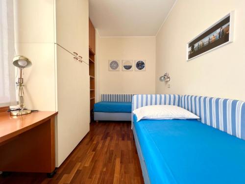 a small room with a blue bed and a refrigerator at Stylish room in milano in Milan