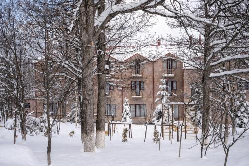an old brick building in the snow with trees at Alpina Resort by Stellar Hotels, Tsaghkadzor in Tsaghkadzor