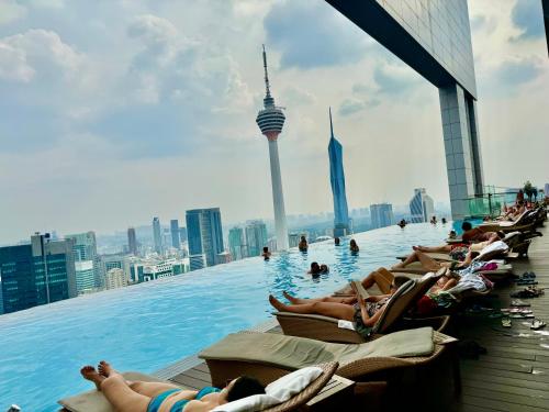 un groupe de personnes se posant dans une piscine à débordement sur le toit d'un bâtiment dans l'établissement Platinum Suites KLCC by Classy, à Kuala Lumpur