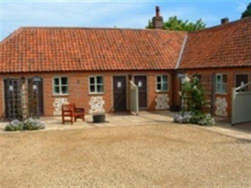 a red brick house with a red roof at The Orange Tree Thornham in Thornham