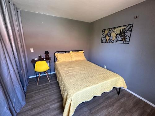 um quarto com uma cama, uma mesa e uma cadeira amarela em Confortável Kitinete Duplex em Fortaleza