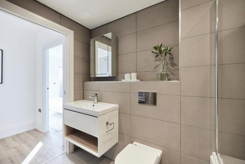 a bathroom with a toilet and a sink and a mirror at The Wembley Park Secret - Spacious 3BDR Flat with Terrace in London