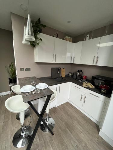 a kitchen with white cabinets and a table in it at Modern Garden Studio for comfy stay in Luton