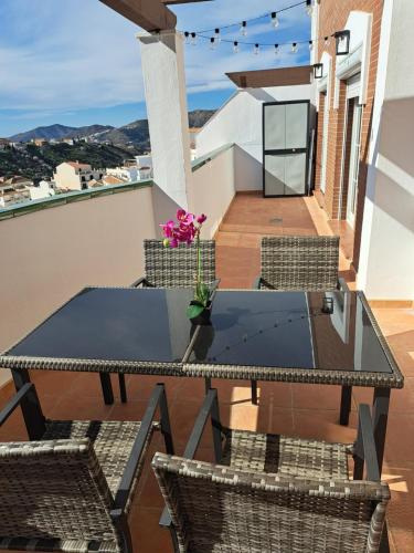 Un patio con una mesa y sillas en un balcón. en Ático Bella Vista, en Cómpeta