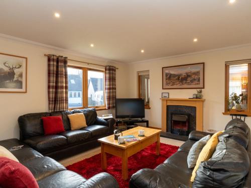 a living room with leather furniture and a fireplace at Villa Craigmore Lodge by Interhome in Aviemore