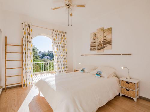une chambre blanche avec un lit et un balcon dans l'établissement Holiday Home Les Chèvrefeuilles by Interhome, à Saint-Aygulf