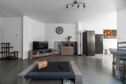 un salon avec une télévision et une table dans l'établissement Le Bardin - Grand appartement design, parking gratuit, à Vichy
