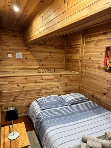 a bedroom with a bed in a wooden wall at Mountain Lodge T3 Duplex Abrigo do Lobo in Covilhã