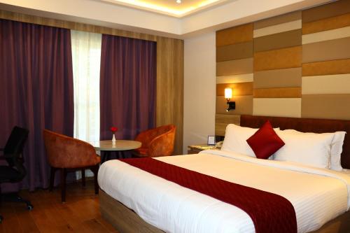 a hotel room with a bed and a table at Capital Park Residency in Trivandrum