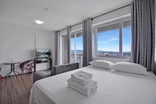 a bedroom with a white bed and a large window at Piscina aquecida Vista Romântica Estacionamento in Osasco