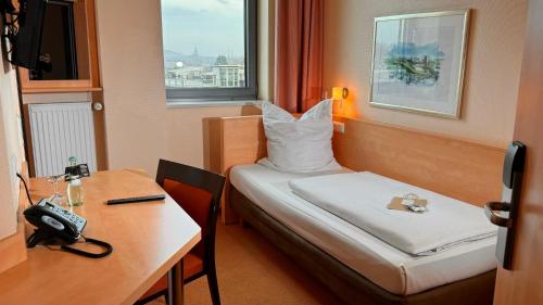 ボトロップにあるHotel Rhein-Ruhr Bottropのベッドと机と電話が備わったホテルの部屋