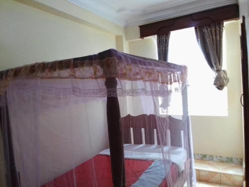 a bed with a canopy in a room with a window at Dreams lodge in Busia