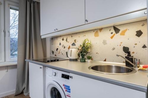 a kitchen with a sink and a washing machine at Passion Fruit Apartment Pge Narodowy in Warsaw