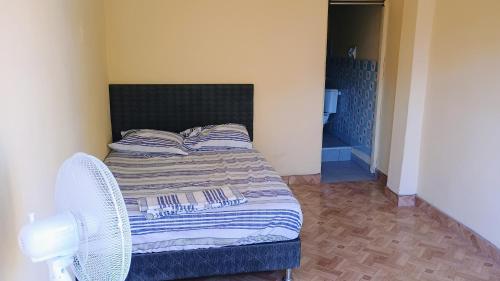 a small bedroom with a bed and two chairs at Casas Cueva in Tumbes