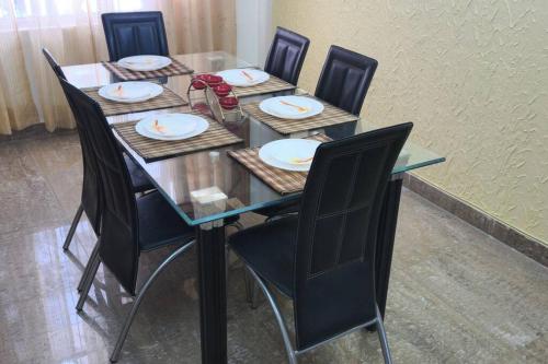 a glass table with chairs and plates on it at Hillside 3BHK with PanoramicView in Solan